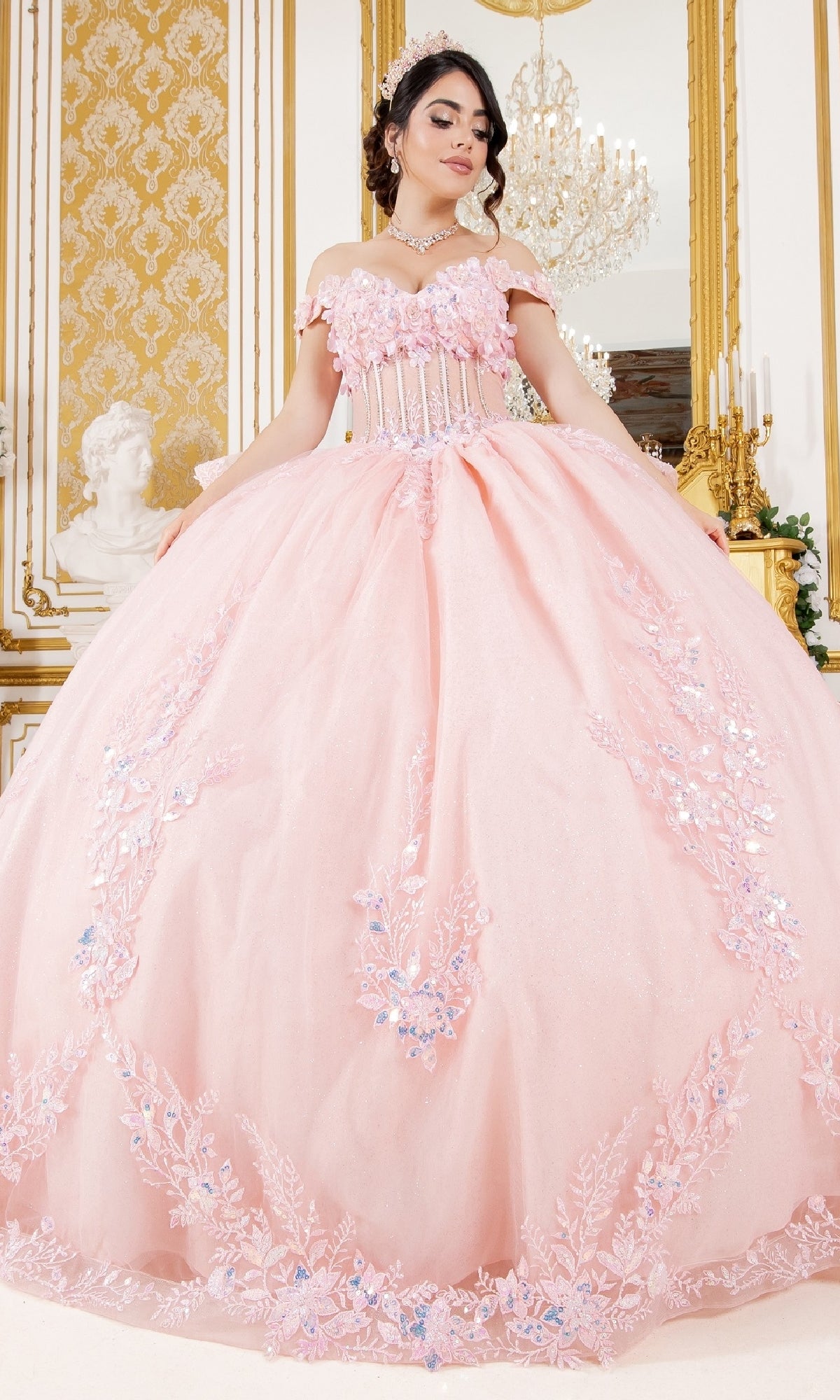 A young woman stands indoors in the Cinderella Couture 8160J quinceanera dress, featuring embroidered lace appliques and off-the-shoulder sleeves, set against an ornate, gold-accented background.